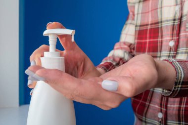 Kadın elleri avuç içine antiseptik jel sıkıyor. Yakın çekim.