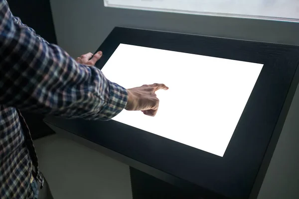 Man touching interactive white blank touchscreen display kiosk at exhibition