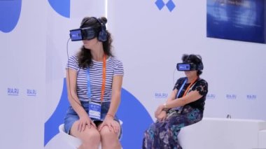 VR teknoloji sergisinde sanal gerçeklik kulaklığı kullanan iki kadın.