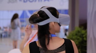 VR teknoloji sergisinde sanal gerçeklik kulaklığı kullanan genç bir kadın.