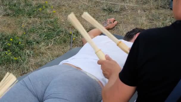 Man händer gör massage för kvinna med bambu pinnar på utomhus yoga festival — Stockvideo