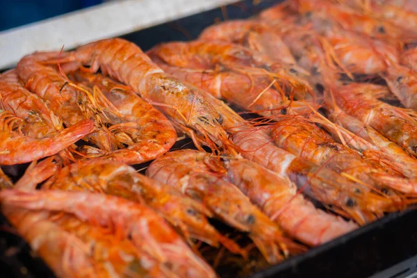 Process of cooking fresh red langoustine shrimps, prawns on grill - street food