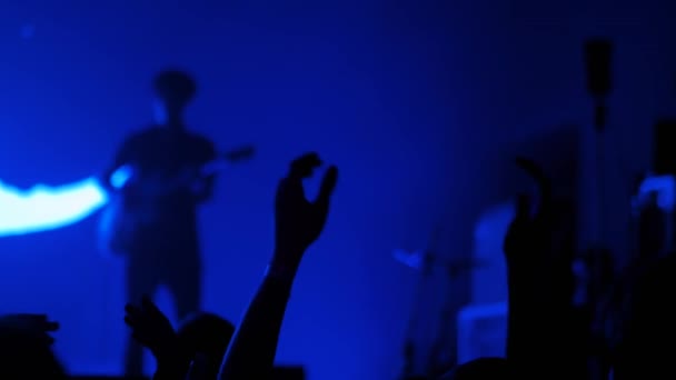 Homem silhueta festa e aplausos no concerto de rock com iluminação azul — Vídeo de Stock