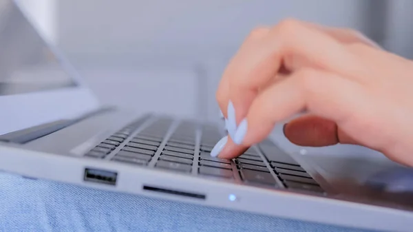 Woman hands typing on laptop computer keyboard - close up side view