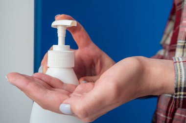 Kadın elleri avuç içine antiseptik jel sıkıyor, ellerini temizliyor. Kapat.