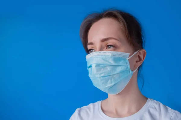 Woman wearing medical face mask, looking away - quarantine concept - close up