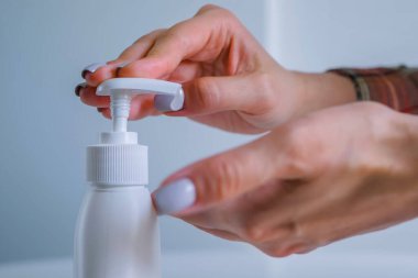 Kadın avuç içine antiseptik jel sıkıyor, ellerini temizliyor. Kapat.