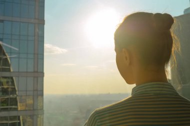 Gökdelen penceresinden şehir manzarasına bakan kadın siluetinin arka planı