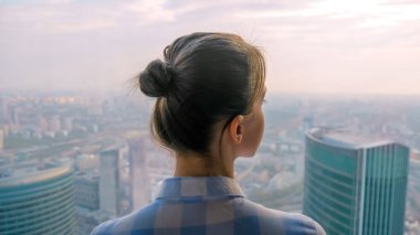 Gökdelen penceresinden şehir manzarasına bakan kadının arka planı