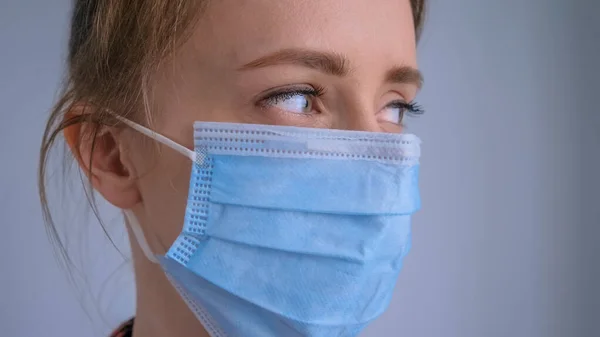 Woman wearing medical face mask, looking away - quarantine concept - close up