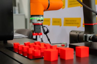 Robot kol manipülatörü robot sergisinde kırmızı oyuncak bloklarını hareket ettiriyor ve yerleştiriyor