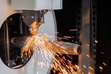 Lazer kesme makinesi, silindirik metal kıvılcımlarla çalışıyor.