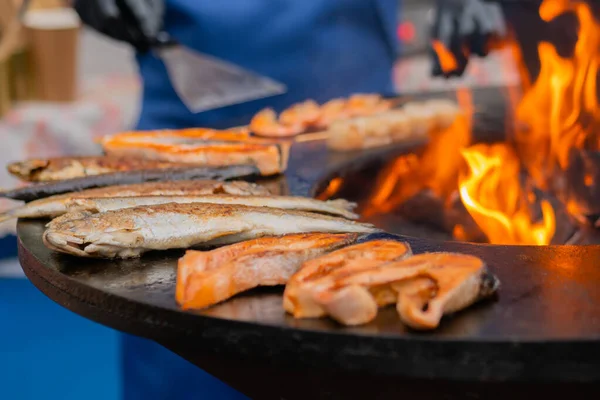 Процесс жарки стейков лосося и макрель рыбы на черной жаровне: закрыть — стоковое фото