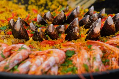 Karides, midye ve büyük tavada pilav ile pişirilmiş sarı paella. Yakın çekim.