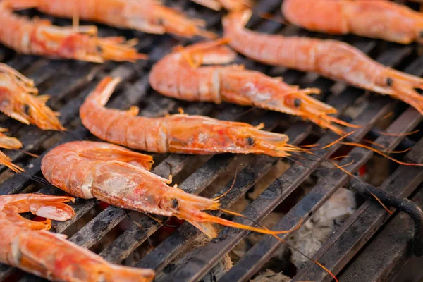 Process of cooking fresh red langoustine shrimps, prawns on grill - street food