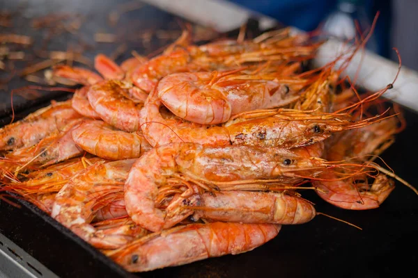 Process of cooking fresh red langoustine shrimps, prawns on grill - street food