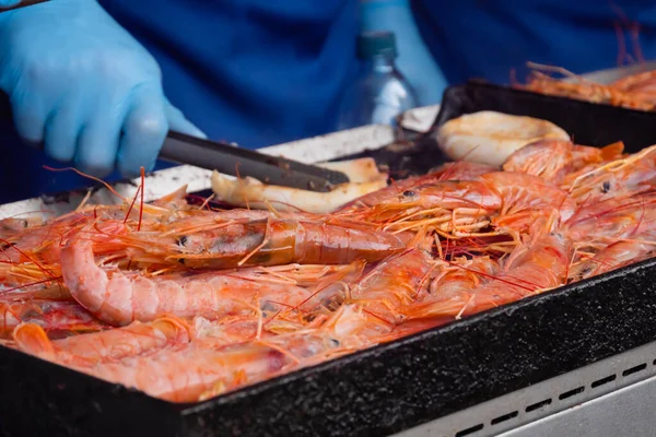 Chef cooking fresh red langoustine shrimps, prawns on grill at summer local food