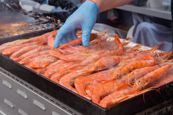 Chef cooking fresh red langoustine shrimps, prawns on grill at summer local food