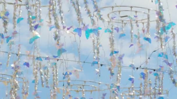 Glänzend hängende Schmetterlingsdekoration wiegt sich im Wind gegen wolkenverhangenen blauen Himmel — Stockvideo
