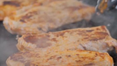 Yakın çekim: Aşçı elinde maşayla Brezilya usulü ızgara et bifteği: Ağır çekim