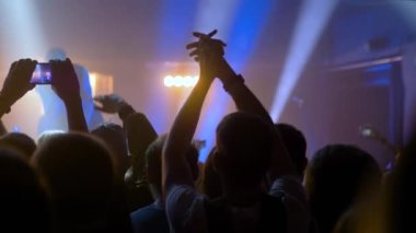 Yavaş çekim: Rock konserinde parti yapan ve alkışlayan insanların siluetleri