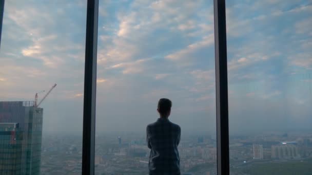 Вид задумчивой женщины, смотрящей на городской пейзаж через окно небоскреба — стоковое видео