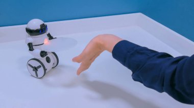 Kadın eli teknoloji sergisinde küçük sevimli robotu kontrol ediyor. Robot gelecek konsepti