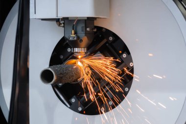 Lazer kesme makinesi, silindirik metal kıvılcımlarla çalışıyor.