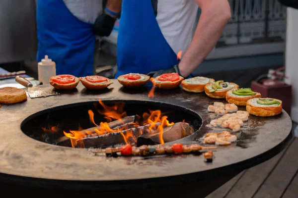 Chef preparar hambúrgueres de peixe no festival de comida de rua ao ar livre - close-up — Fotografia de Stock