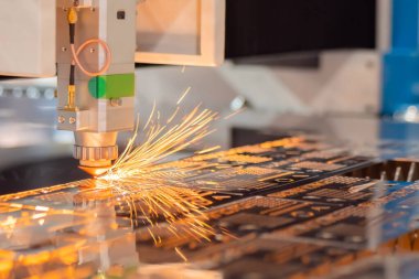 Lazer kesme makinesi fabrikada kıvılcımlarla metal levha ile çalışıyor.