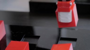 Robot kol manipülatörü robot sergisinde kırmızı oyuncak bloklarını hareket ettiriyor ve yerleştiriyor