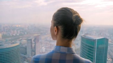 Gökdelen penceresinden şehir manzarasına bakan kadının arka planı