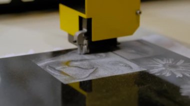 Taş oyma makinesi siyah granit mezar taşına resim oyuyor. Kapatın.