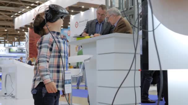 Menino usando fones de ouvido de realidade virtual na exposição de tecnologia VR — Vídeo de Stock