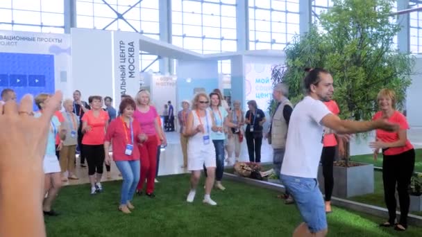 Groupe de personnes âgées faisant de l'exercice de qigong ensemble à l'exposition sportive — Video