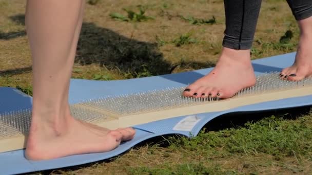 Pies de mujer caminando descalzos sobre tablas de madera con clavos afilados en el festival de yoga — Vídeos de Stock
