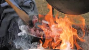 Ağır çekim: elinde spatula olan bir adam, tavada tavada et kızartıyordu.