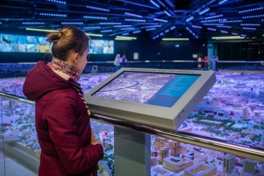 Modern müzede ya da sergide etkileşimli dokunmatik ekran kullanan kadın