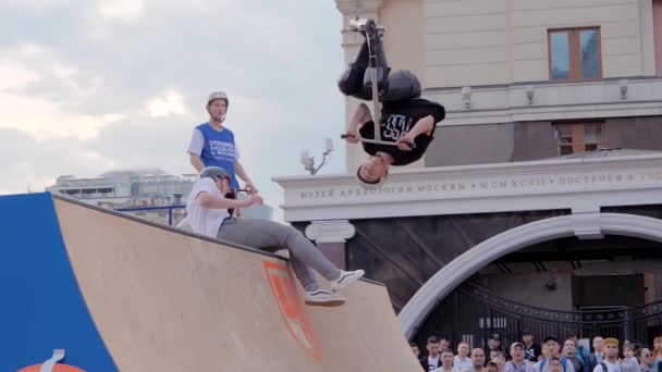 Adolescente mostrando trucos de salto sobre la gente en scooter en skatepark — Vídeos de Stock