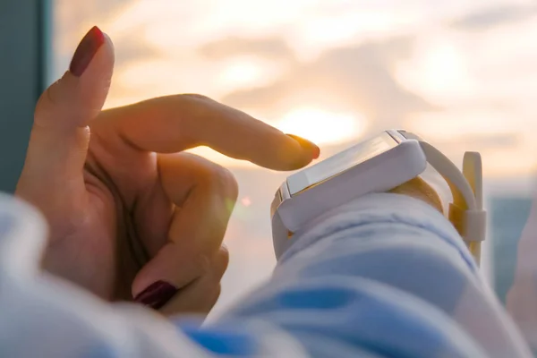 De cerca: mujer usando reloj inteligente blanco usable contra el cielo cálido atardecer — Foto de Stock