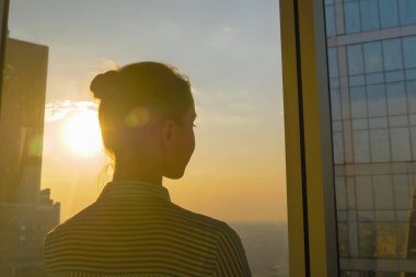 Gökdelenin cam penceresinden şehir manzarasına bakan kadının arka planı