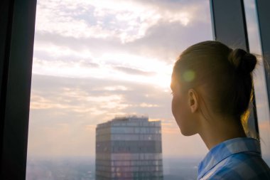 Gökdelen penceresinden şehir manzarasına bakan kadın - güneş mercekleri parlıyor