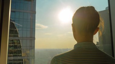 Gökdelen penceresinden şehir manzarasına bakan kadın siluetinin arka planı