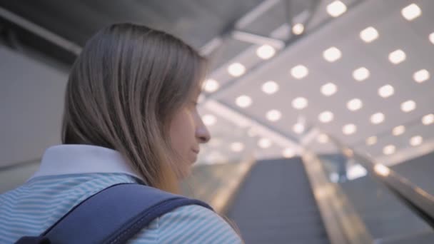 Ung kvinna flyttar på rulltrappan och ser sig omkring - slow motion — Stockvideo