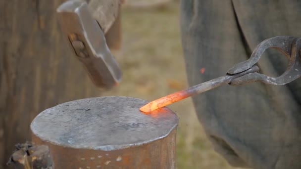 Кузнец, работающий с металлом на наковальне на открытом воздухе - замедленная съемка, крупный план — стоковое видео