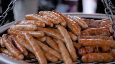 Büyük yuvarlak ızgarada taze et sosisi pişirme işlemi. Yavaş çekim.