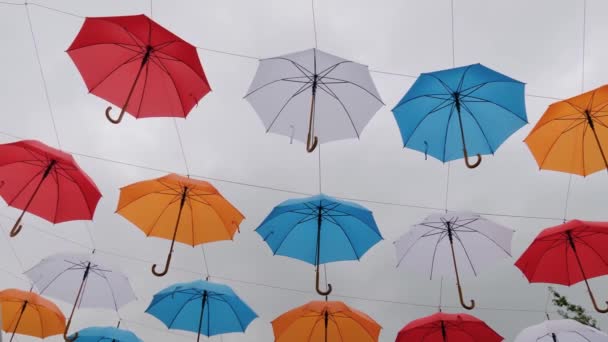 Guarda-chuvas coloridos pendurados contra o céu nublado no festival ao ar livre: câmera lenta — Vídeo de Stock