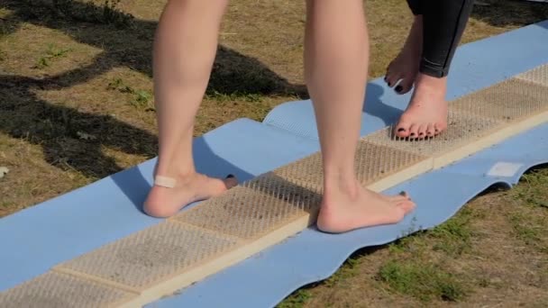 Kvinnliga fötter går barfota på träbrädor med vassa naglar på yogafestivalen — Stockvideo