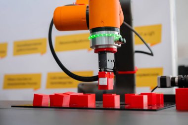 Robot kol manipülatörü robot sergisinde kırmızı oyuncak bloklarını hareket ettiriyor ve yerleştiriyor