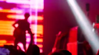 İnsanlar rock konserinde sahnenin önünde siluet partileri düzenliyor.